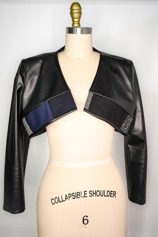 Cropped black faux leather bolero with a mix of wool fabric hemline. One-of-a-kind statement piece.