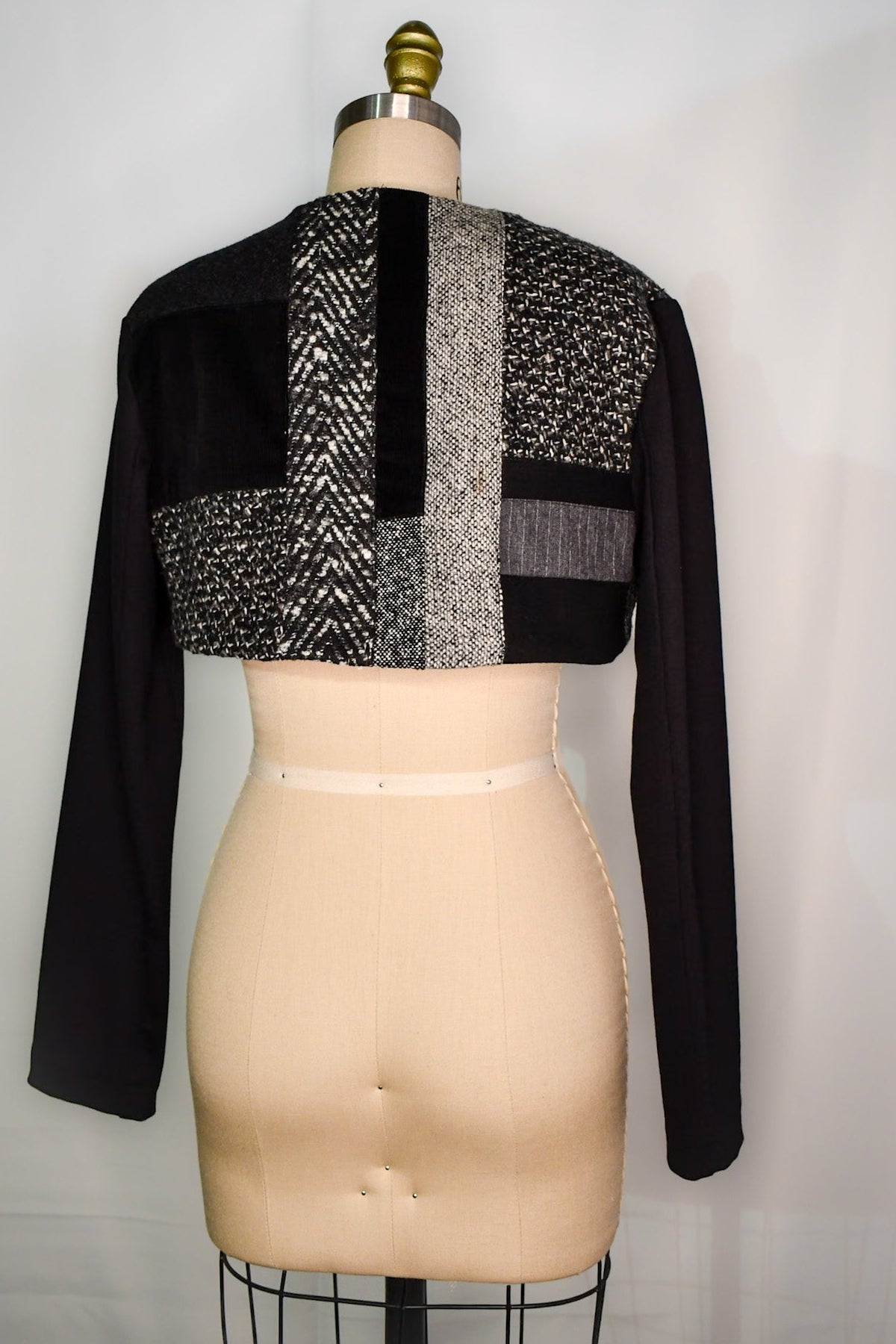 Black and grey mix of wool fabrics on the back side of a cropped bolero jacket.